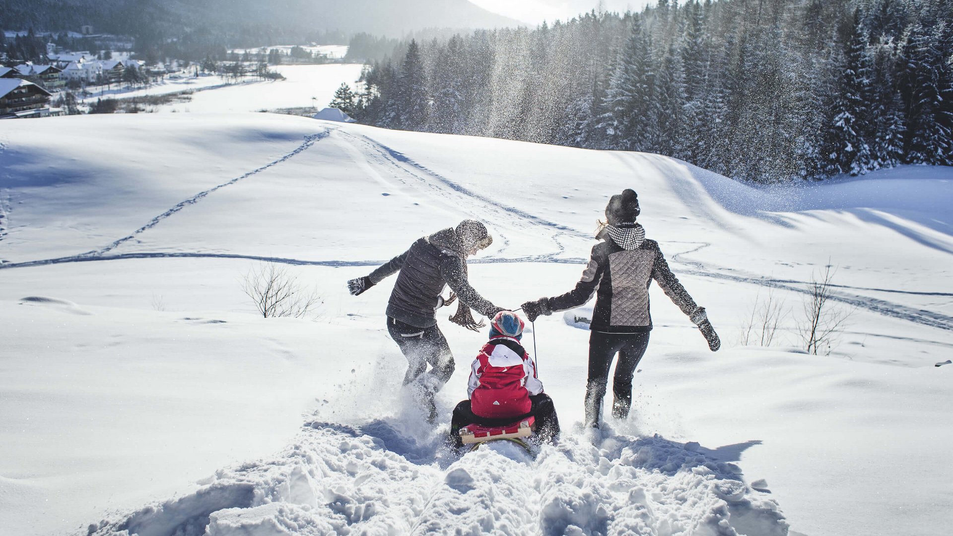 Ihr Urlaub in Seefeld in Tirol Drei Personen genießen Schlittenfahren im verschneiten Bergtal bei Sonne